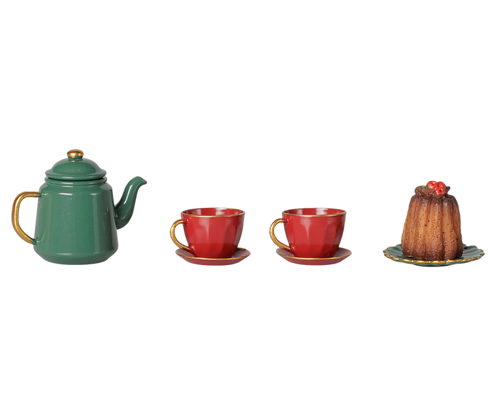 A miniature tea set and dessert display featuring a green teapot with gold accents, two red teacups with saucers, and a small brown pudding on a plate, arranged on a plain white background.