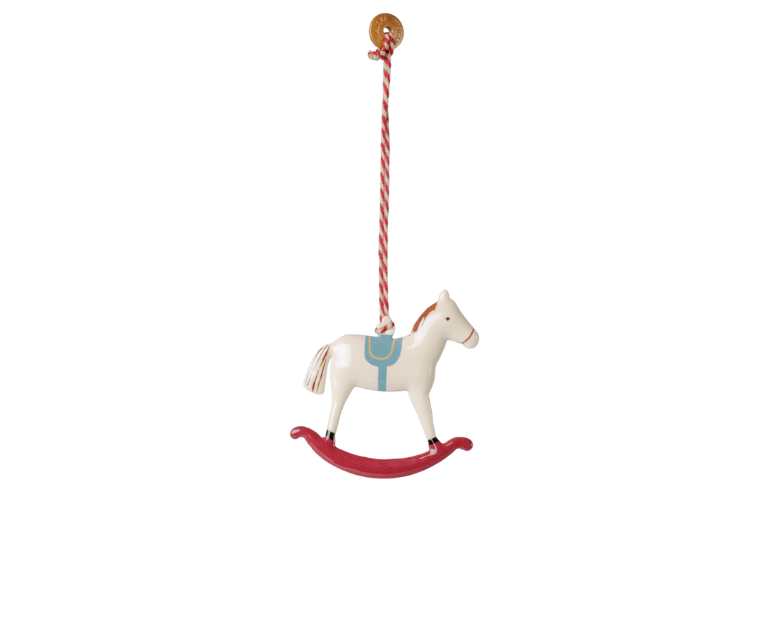 Maileg white metal rocking horse Christmas ornament with blue saddle, red rocker, and red striped hanging string. 